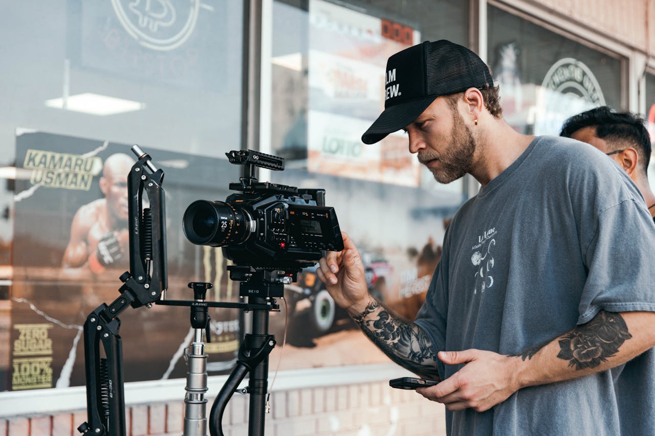 A filmmaker adjusting a professional camera setup outdoors, capturing video content.