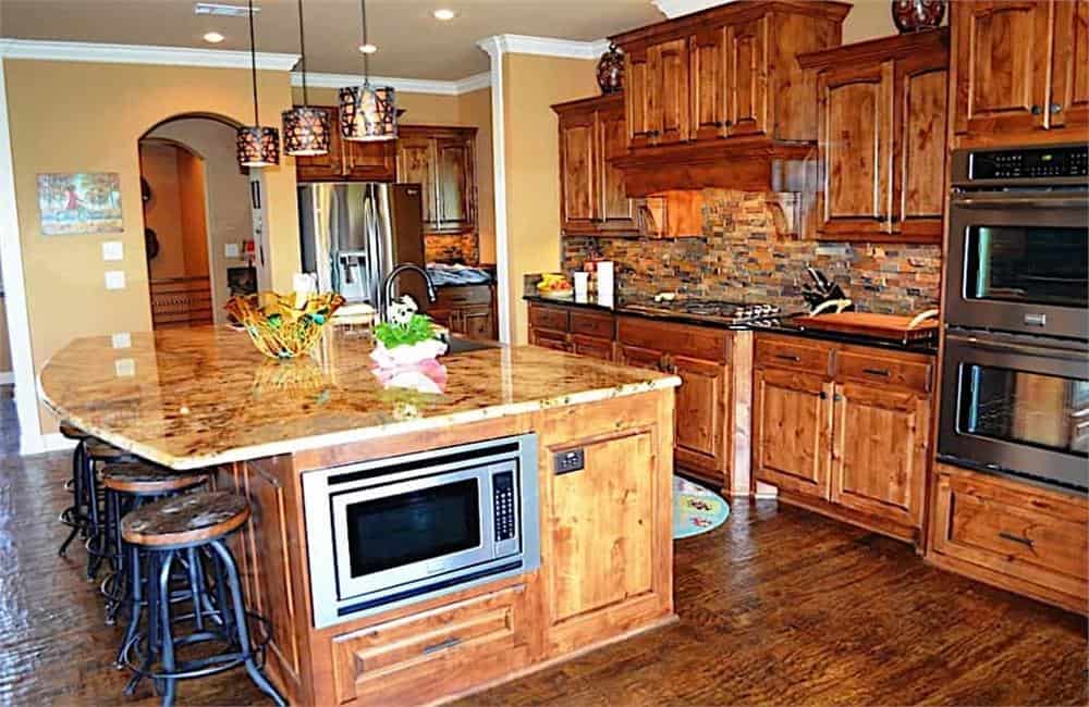 Kitchen with natural wood cabinetry, granite countertops, and a large breakfast island paired with round bar stools.