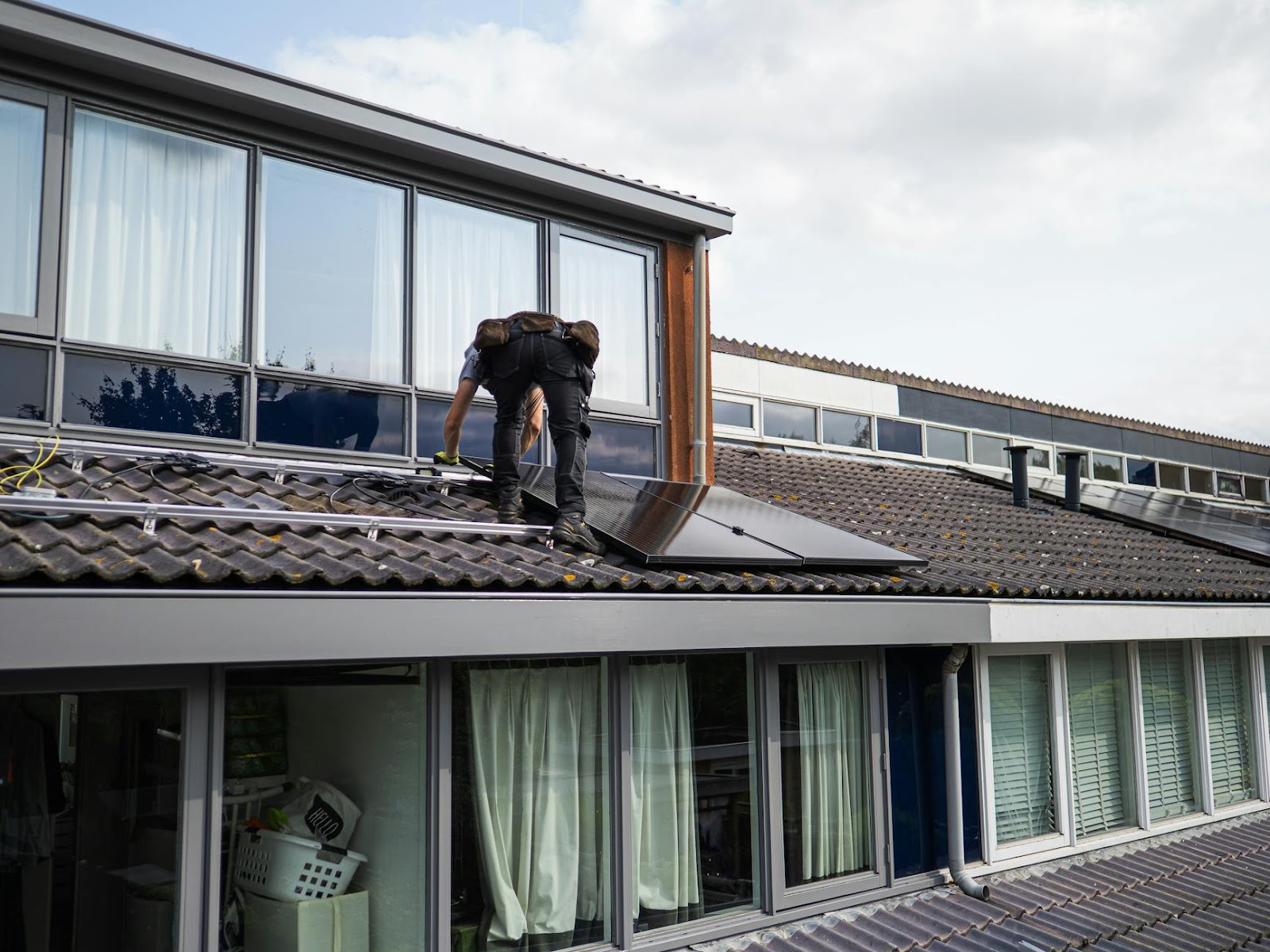 Technician working on installing solar panels on a residential rooftop during the day