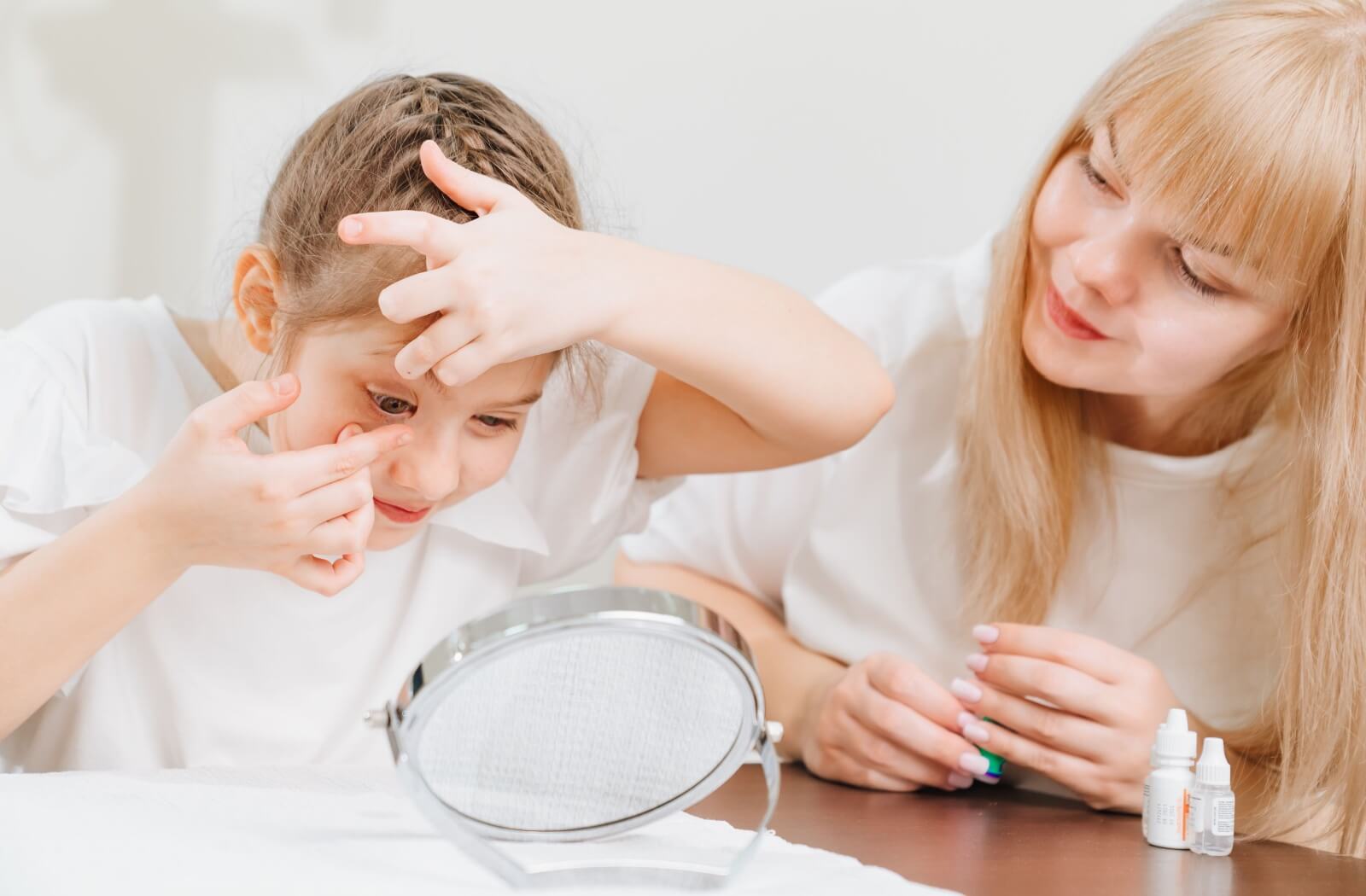 A parent assists their child with putting in their ortho-k lens.