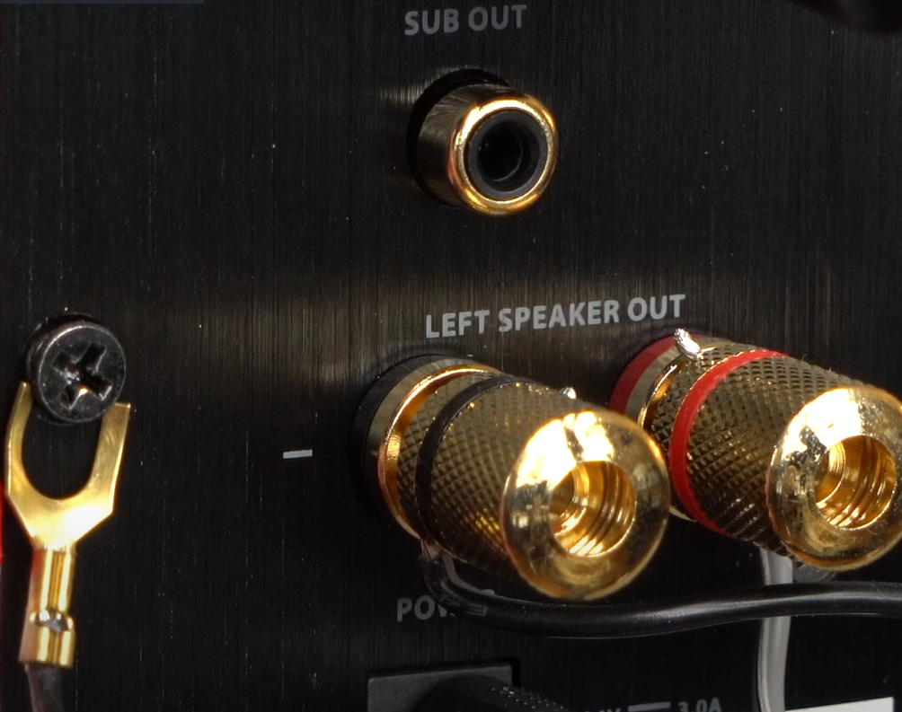 Close-up of gold-plated left speaker out and sub out connections on an audio amplifier.