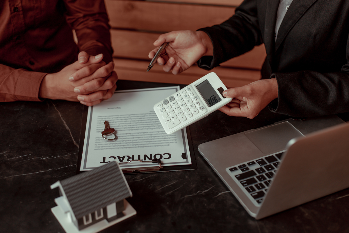 Two people discussing and signing a house sale contract at a table