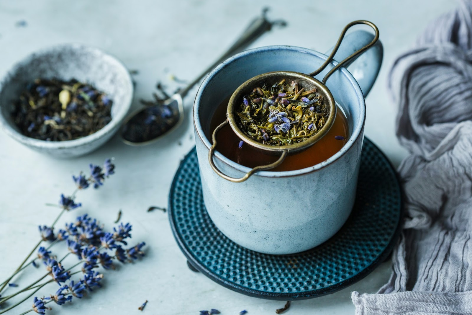 An aesthetic shot of lavender been strained into a tea cup with water beneath it