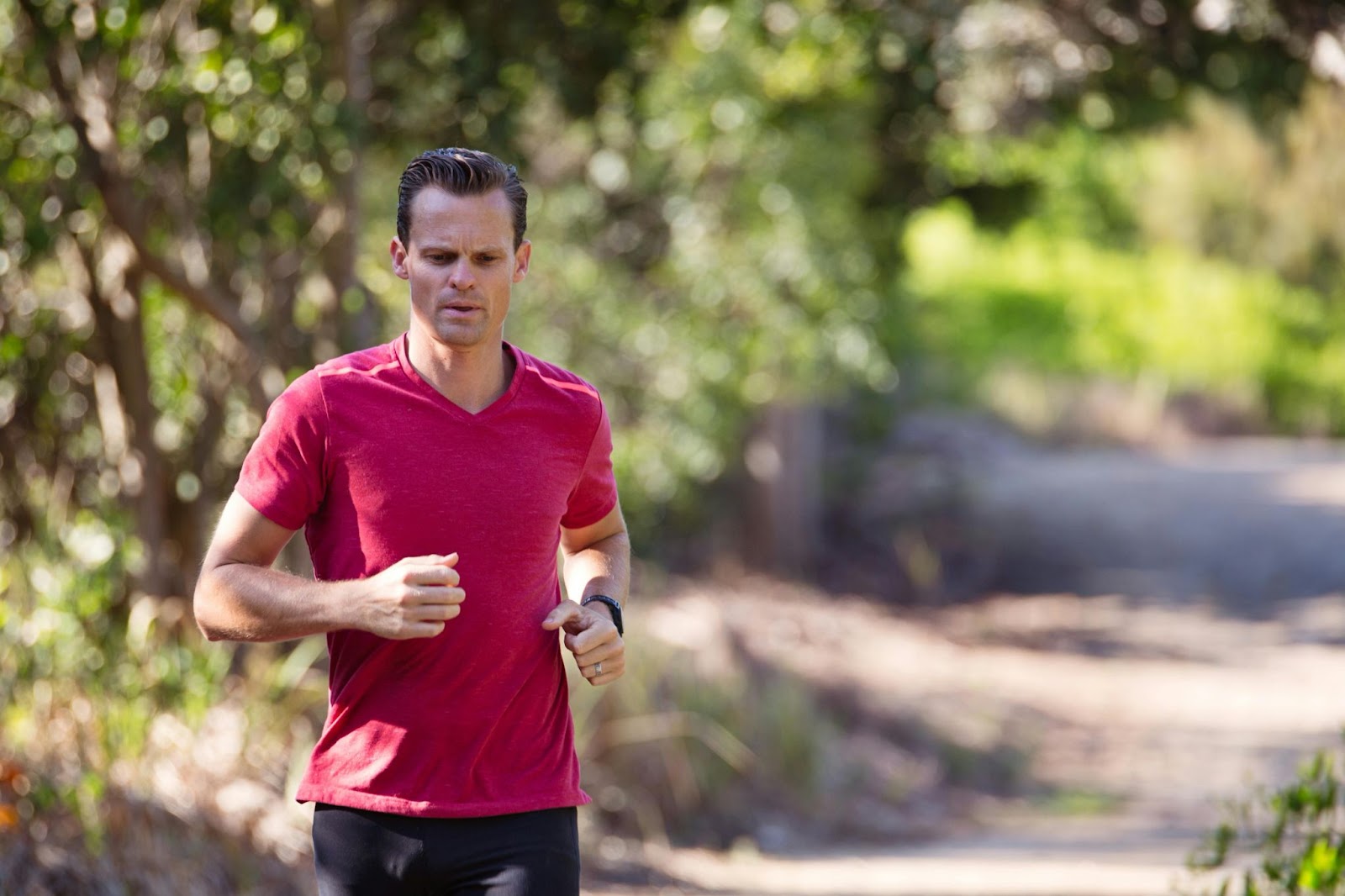 A man jogs on a path in a park.
