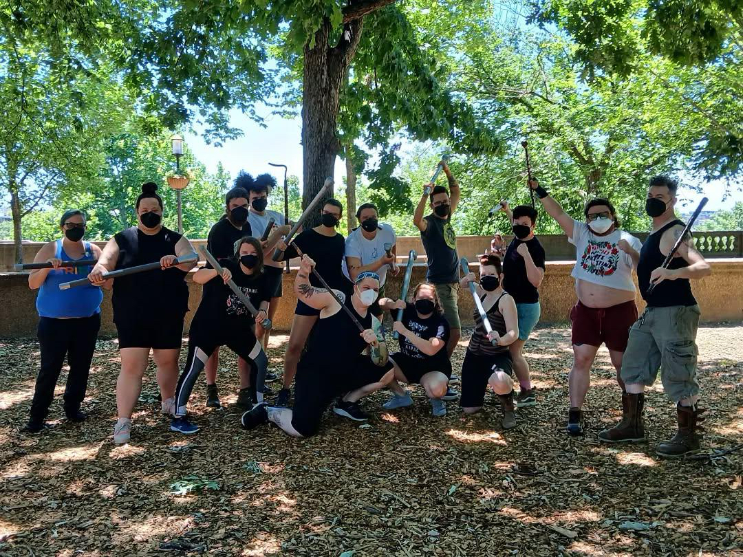 A group of people with martial arts gear post for an outdoor photo.