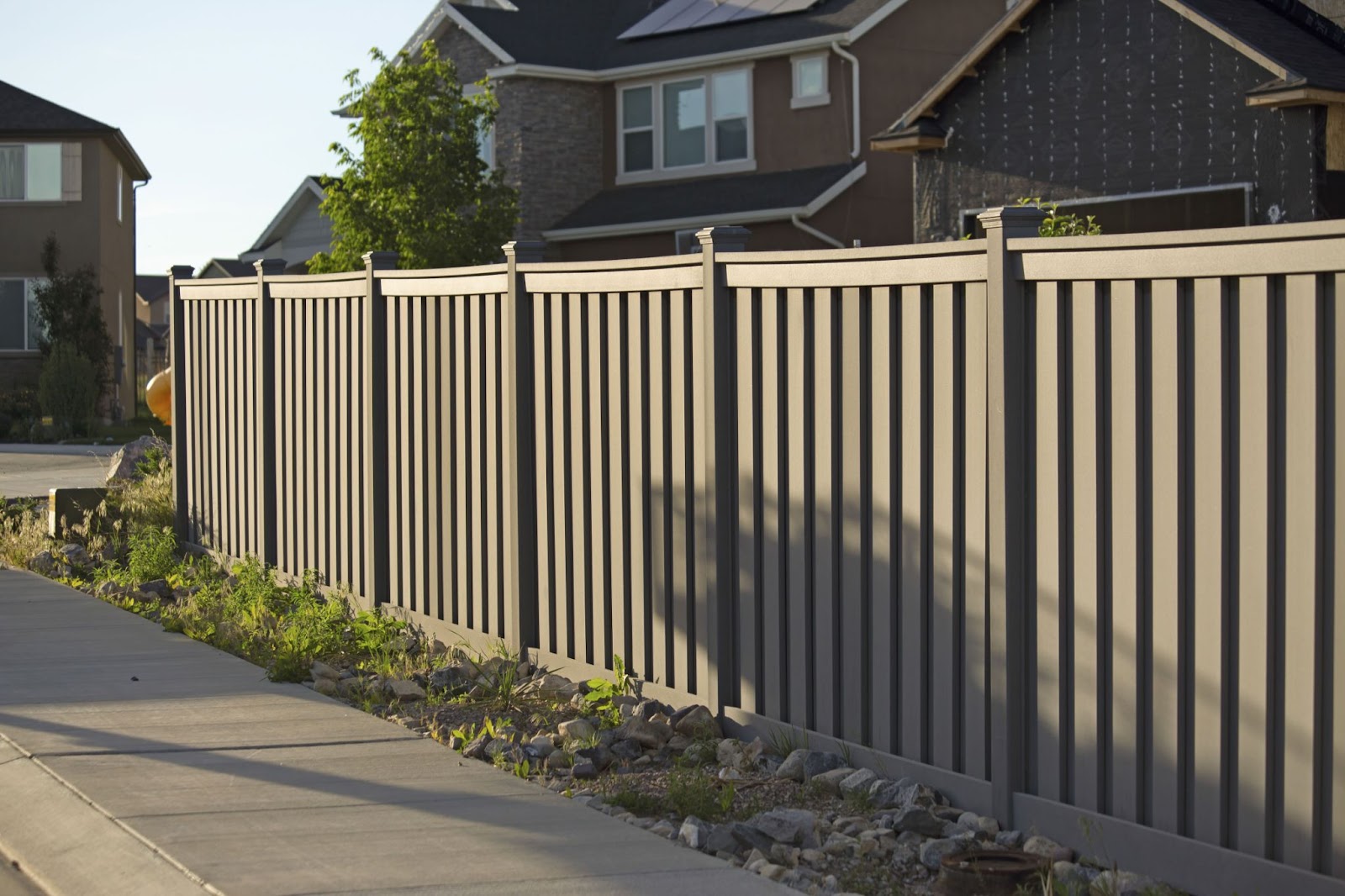 Gray vinyl fence around a home next to a sidewalk. 