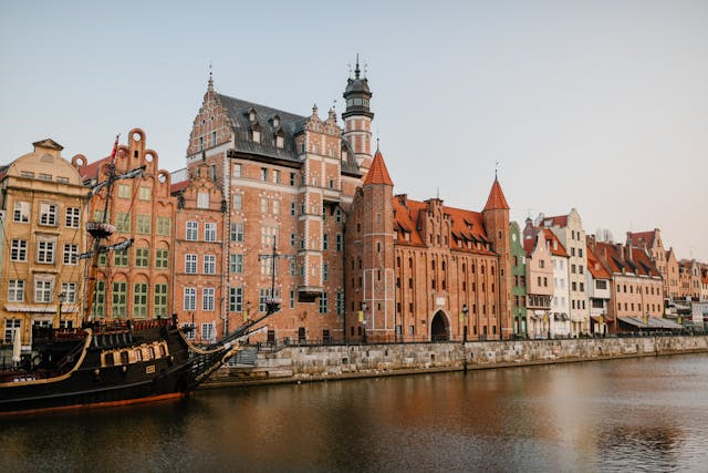 A picturesque view of Gdańsk's historic waterfront showcases colorful, ornate buildings reflecting in the calm river, embodying the city's rich cultural heritage.