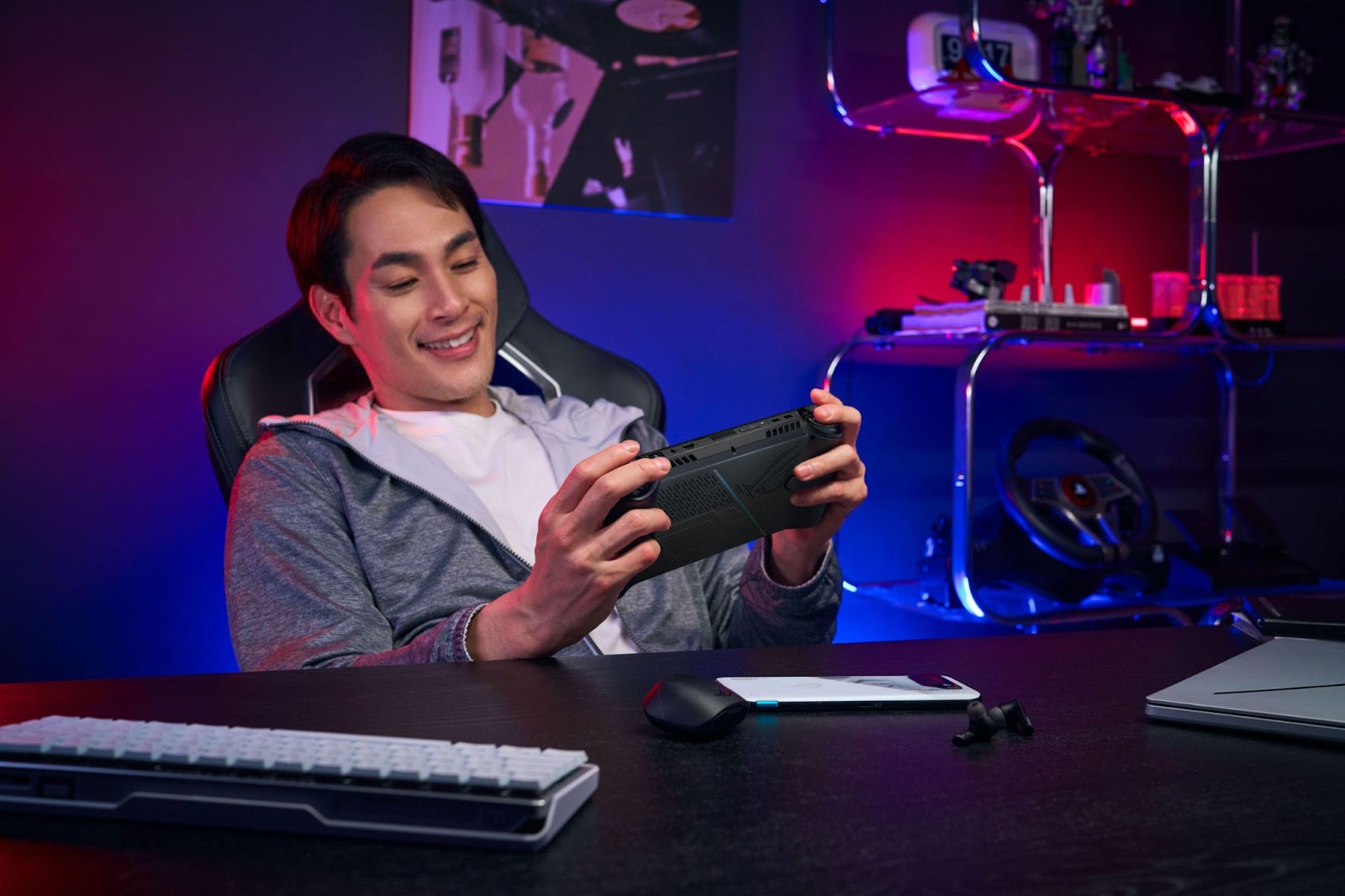 Homem jogando com rog ally, com teclado mecânico branco, mouse e smartphone sobre a mesa.
