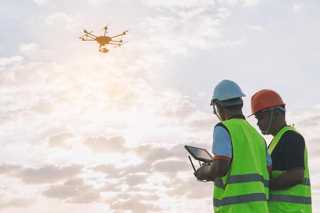 People flying drone while standing on road against sky