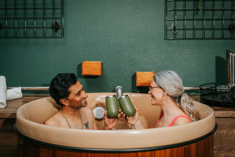 Man and woman smiling at each other while relaxing in a beer bath at Oakwell Beer Spa in Denver