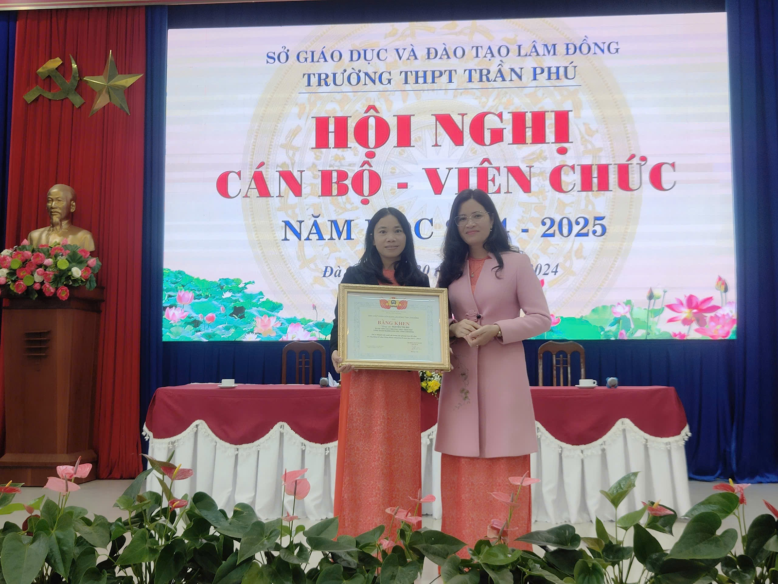 Two women standing at a podium with a plaque

Description automatically generated