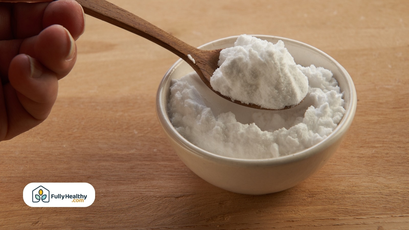 Hand scooping baking soda from bowl