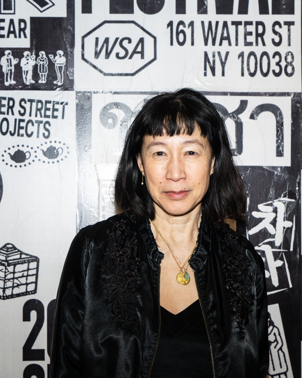 A woman looks into the camera against a black and white poster backdrop. 