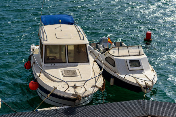 Two boats docked side by side with red fenders