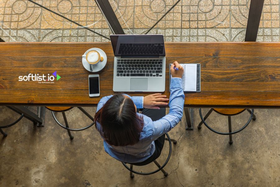 Woman working on a laptop in a cozy café with a notebook.