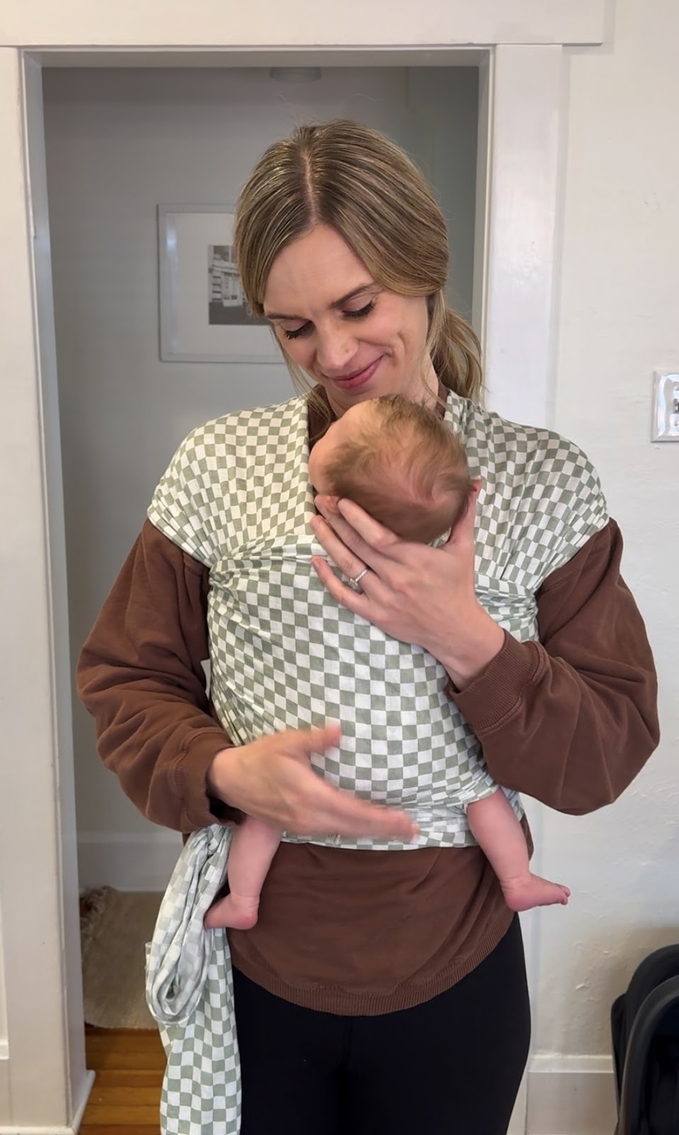 Parent wearing a newborn in a Solly Baby Wrap, featured in baby carrier reviews.