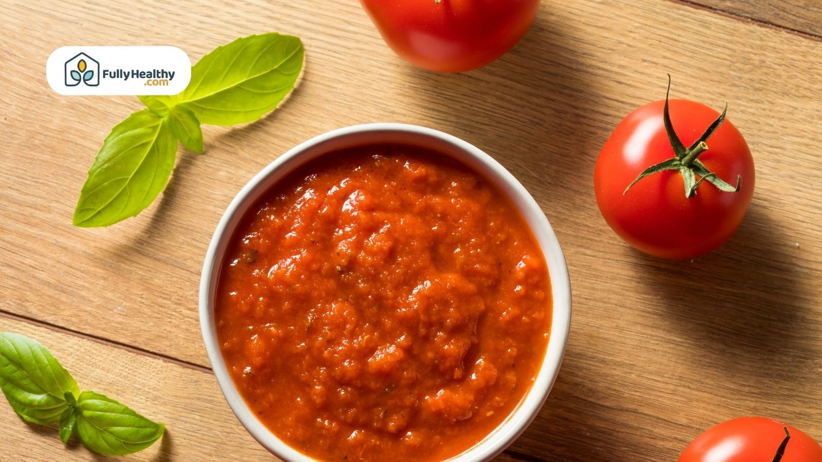 Bowl of tomato sauce with tomatoes and basil on wooden surface
