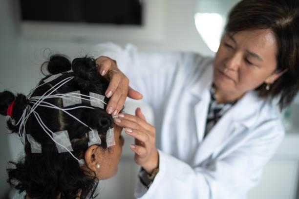 Doctor placing electrodes on patient's head for a polysomnography (sleep study) Doctor placing electrodes on patient's head for a medical exam Neurofeedback Devices stock pictures, royalty-free photos & images