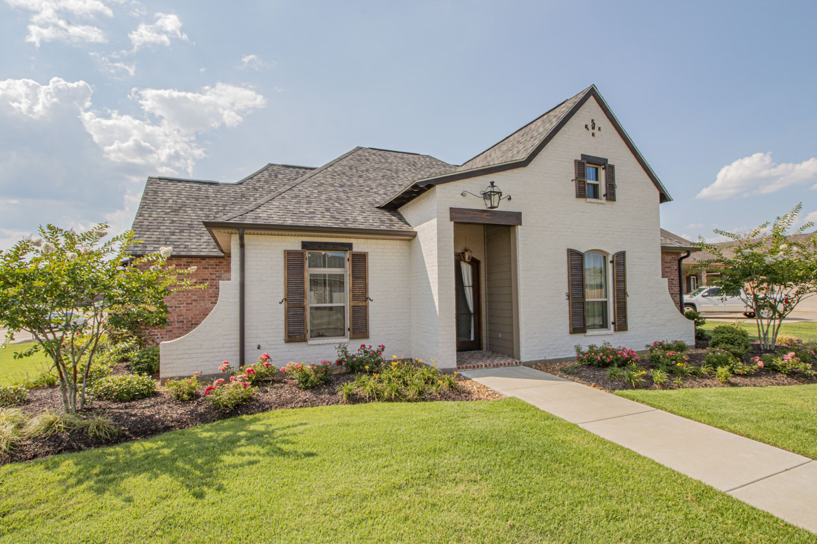 Simple house surrounded by a freshly mulched garden featuring small bushes and blooming flowers.