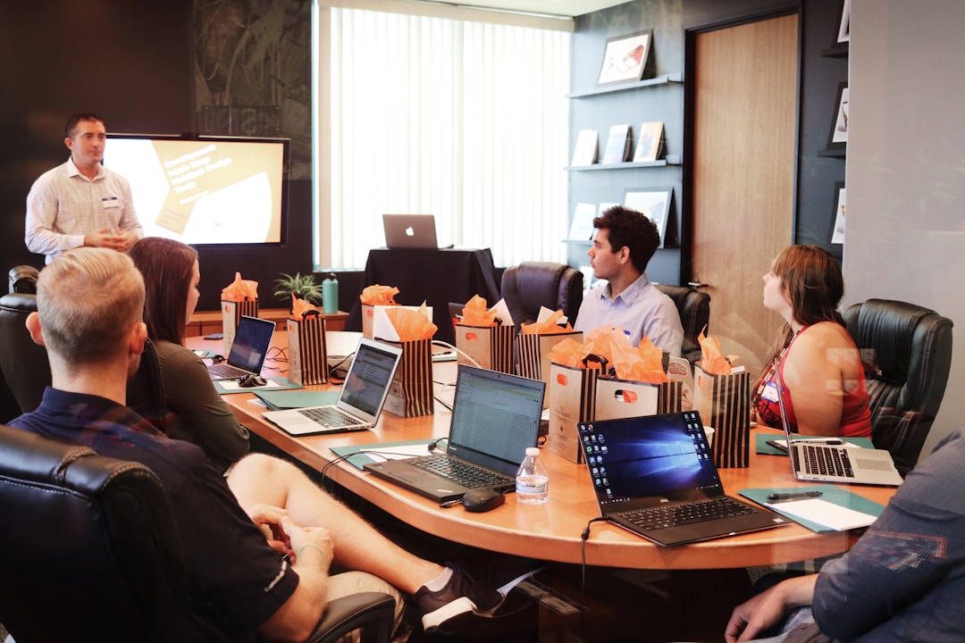 A diverse group of people at a table with laptops, actively sharing ideas on ServiceNow knowledge alternatives.