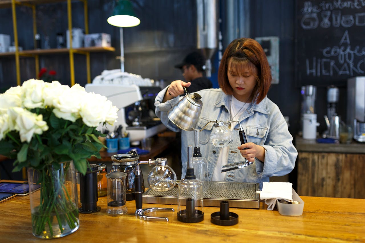 Woman pouring coffee into cup at cozy cafe.