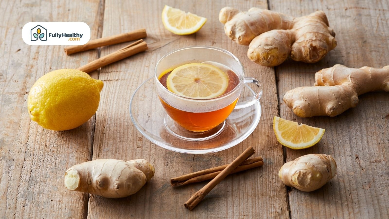 Ginger tea with lemon slices surrounded by ginger and cinnamon sticks