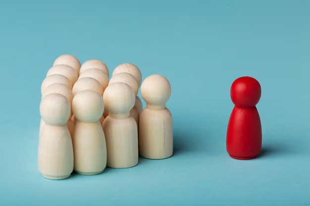 A group of white wooden peg figures stands together on the left, while a single red wooden peg figure is positioned separately on the right against a light blue background.