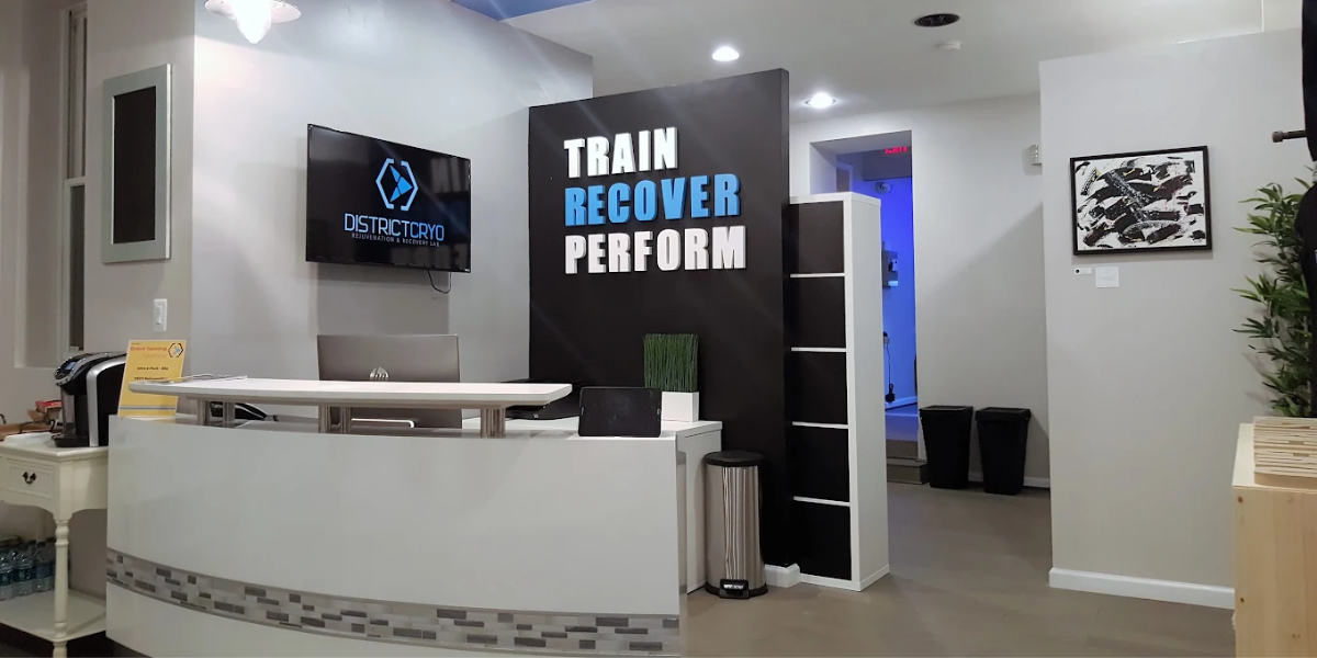 Reception desk with a sign reading "Train Recover Perform," highlighting District Cryo's focus on wellness and recovery.