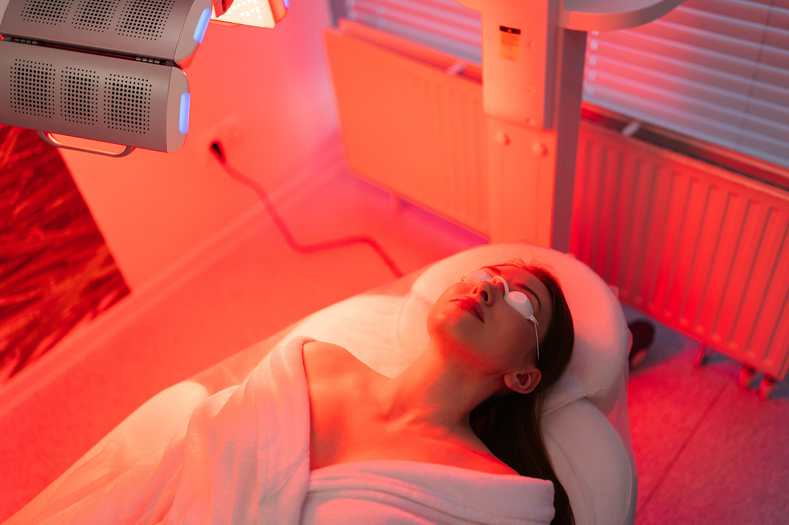 Người phụ nữ đang trị liệu với ánh sáng đỏ trong không gian spa, đang nằm thư giãn và chăm sóc da. Bài viết cung cấp thông tin về tác dụng của liệu pháp ánh sáng đỏ, cách sử dụng và những lưu ý để đạt kết quả tối ưu trong việc làm đẹp.