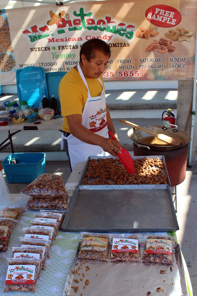 A man is cooking and serving food and packing in packets' Packets are putting in trays and on the table