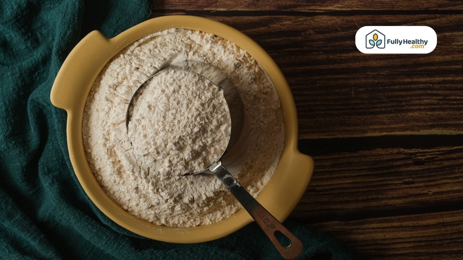 Measuring cup in bowl of almond flour on dark wooden background