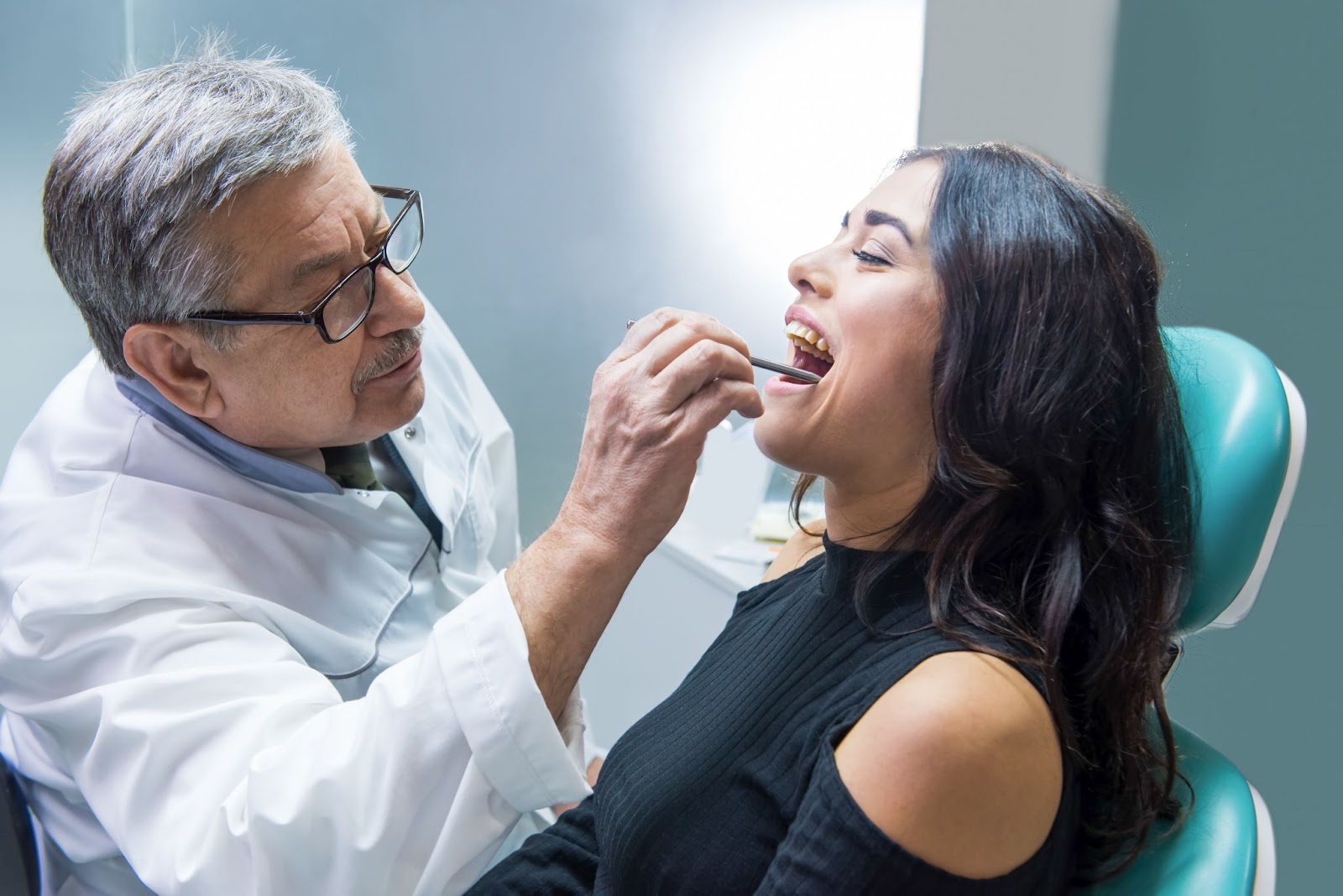 Male dentist examining a woman’s teeth. 