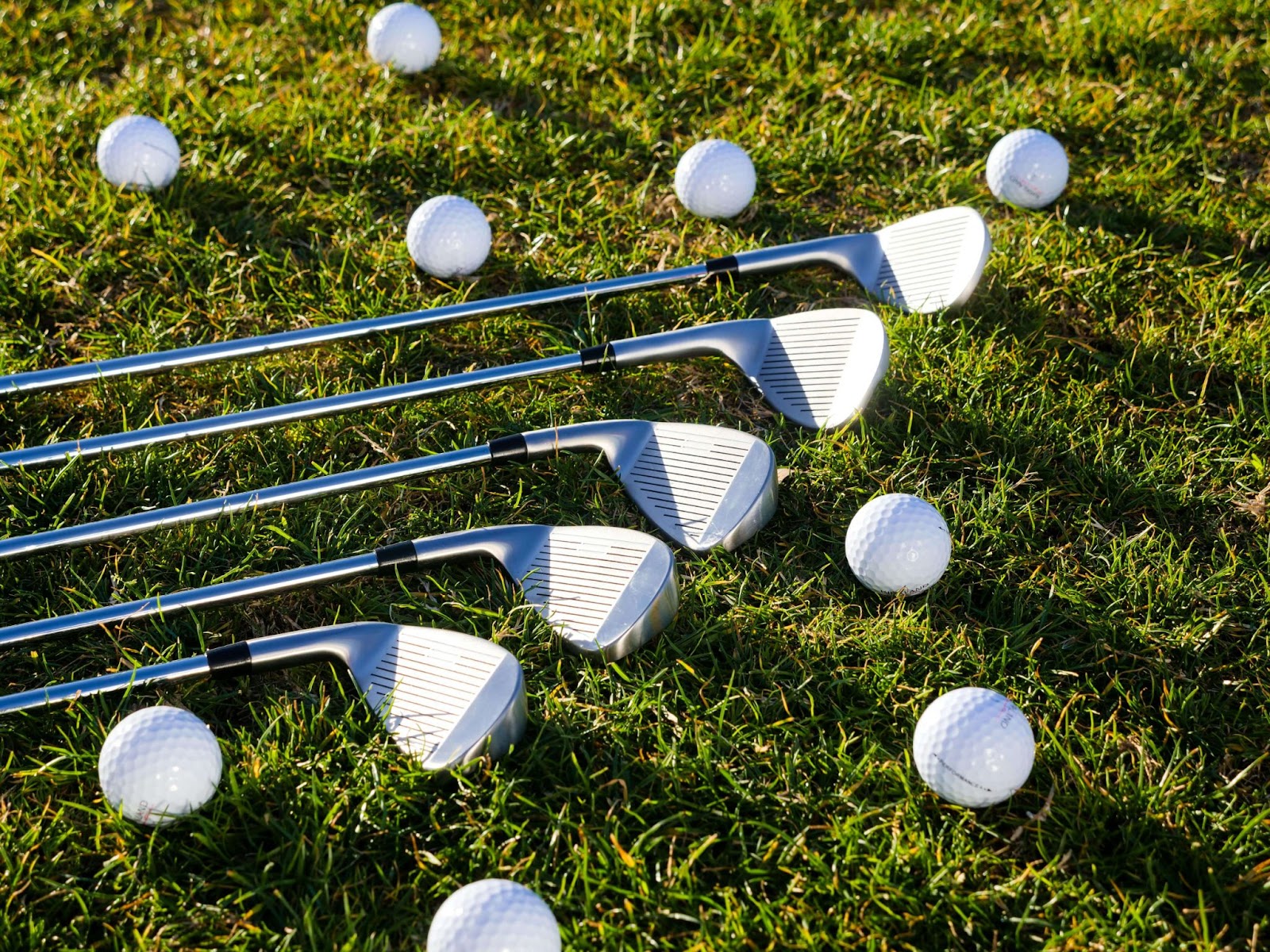 golf clubs and golf balls on grass
