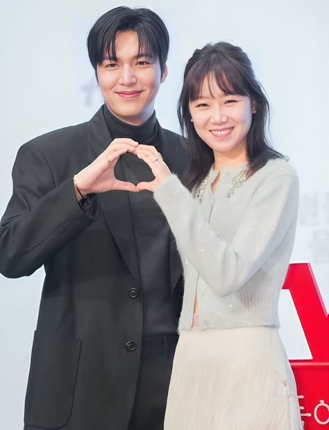 This contains an image of  Lee Min Ho and Gong Hyo Jin standing next to each other with their hands in the shape of a heart