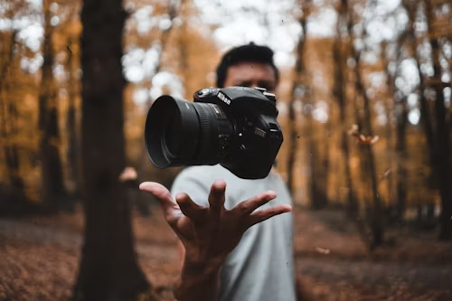 photographer tossing a DSLR camera in the air in an autumn forest