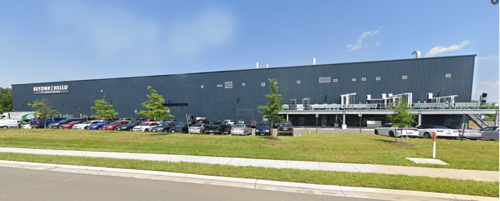 Facade of a large cannabis processing factory with large parking spaces.