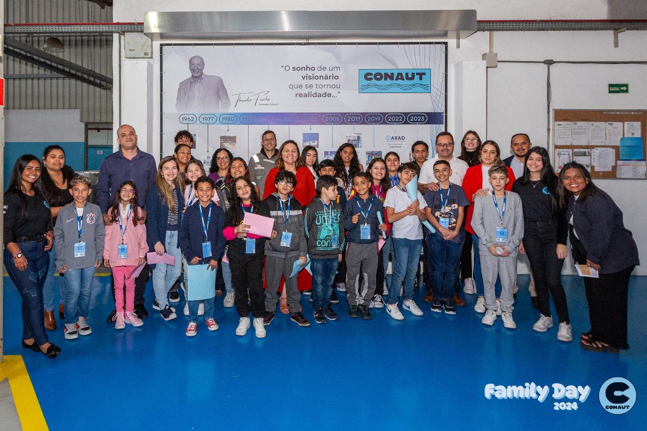 Grupo de pessoas posando para foto em frente a parede azul

Descrição gerada automaticamente com confiança baixa