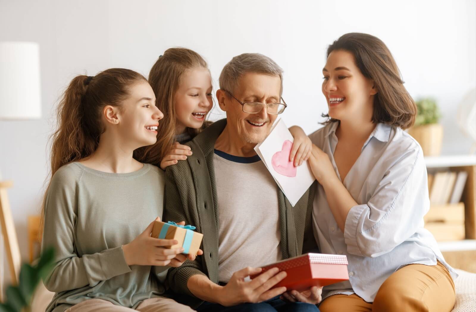 A senior opens gifts with their adult child and grandchildren.