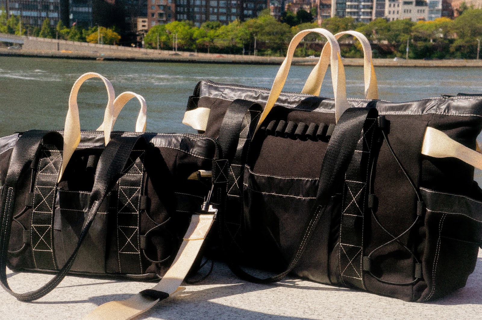 Both sizes of the FHD Utility Tote displayed outdoors, against a city skyline. 