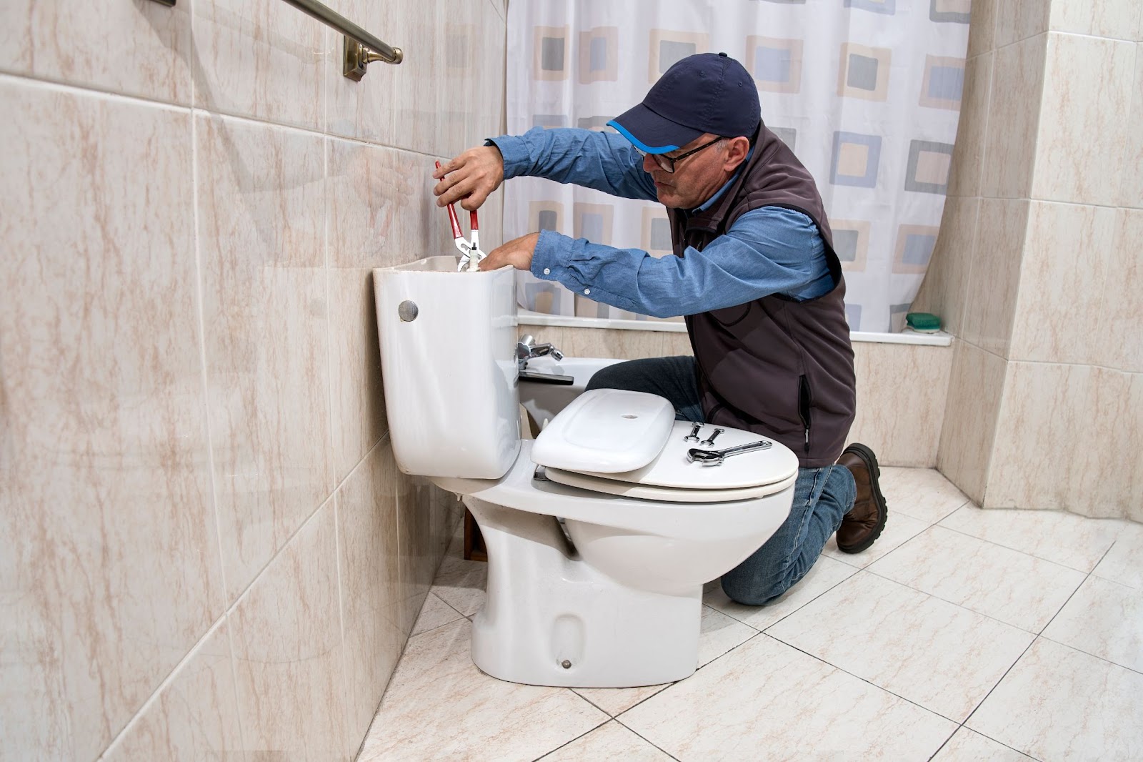 Plumber using tools to repair a toilet. 