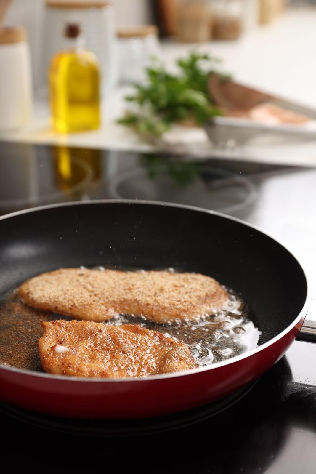 veal cutlets frying in a pan till golden brown