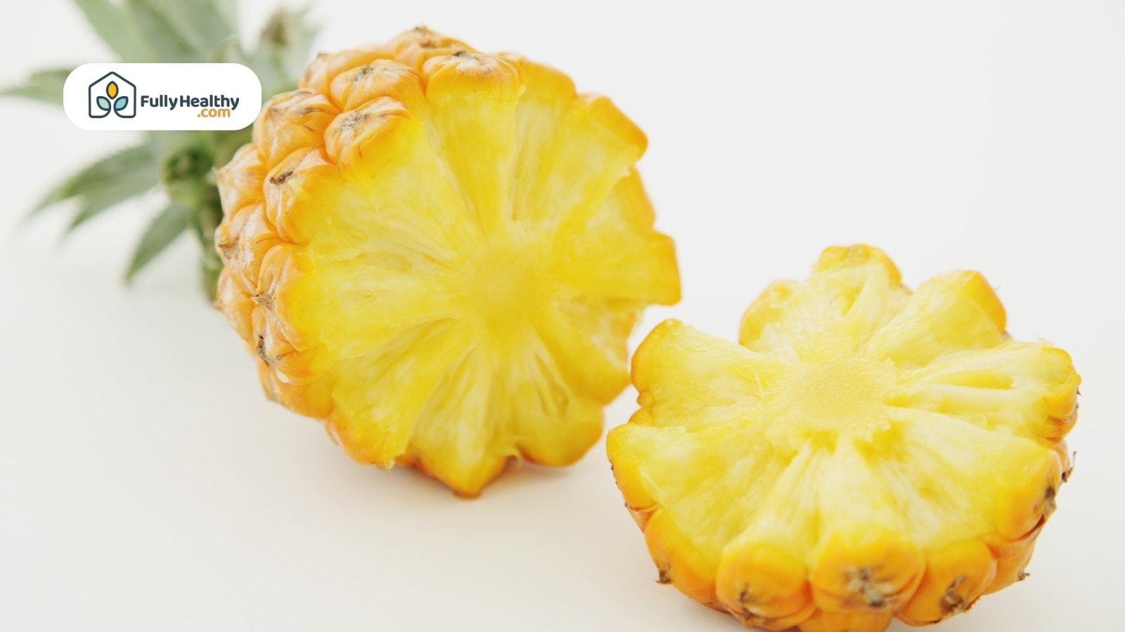 Halved ripe pineapple with yellow flesh on white background surface