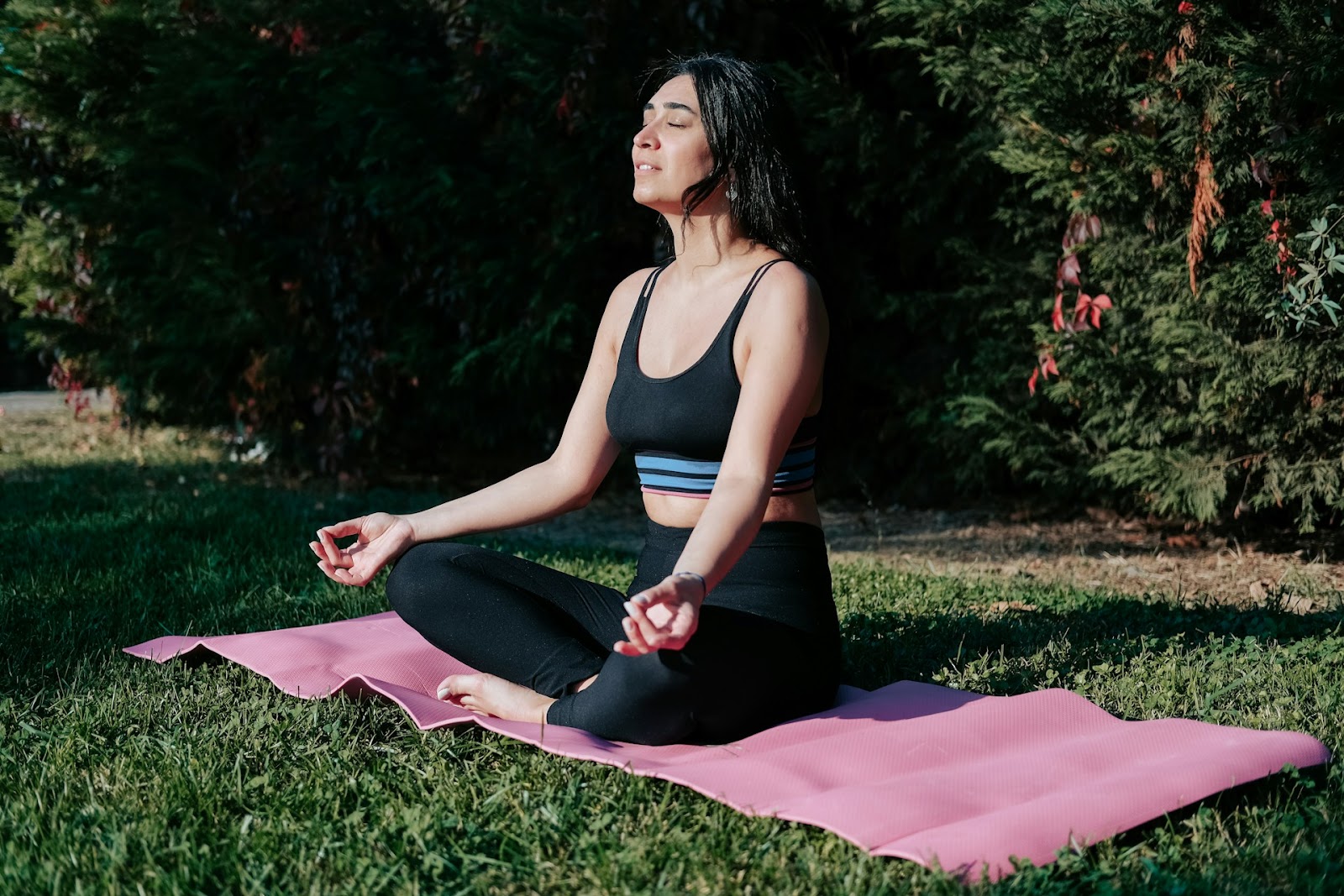 A woman sits outside on a yoga mediating