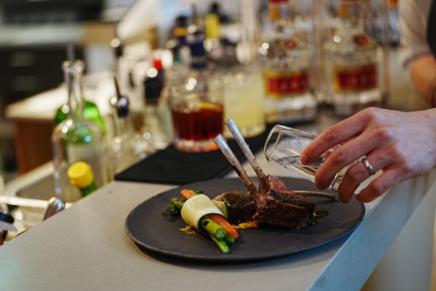A hand pouring a glass of liquid onto a plate of meat

AI-generated content may be incorrect.