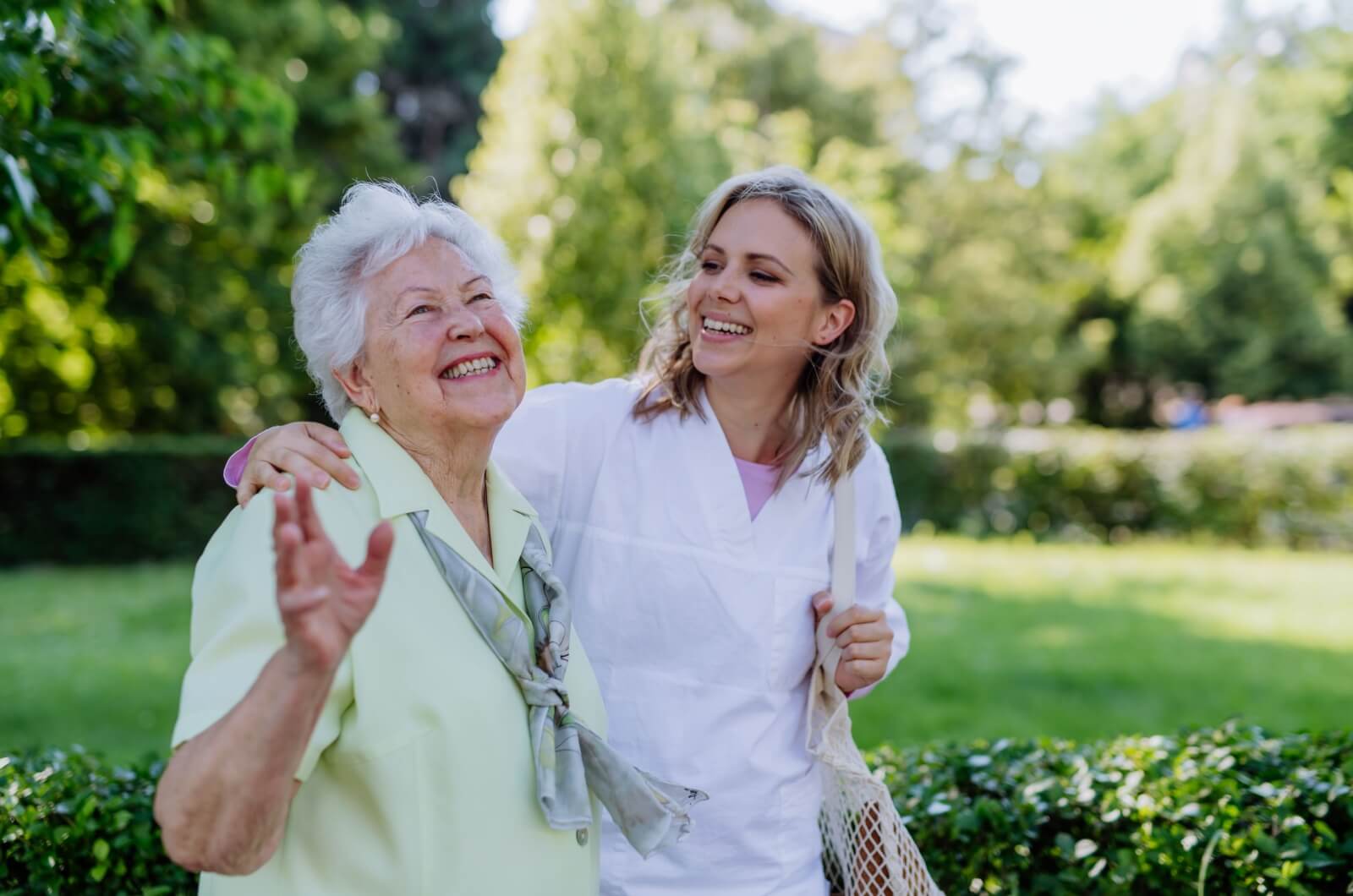 A happy adult child and their mother walking in a public garden.