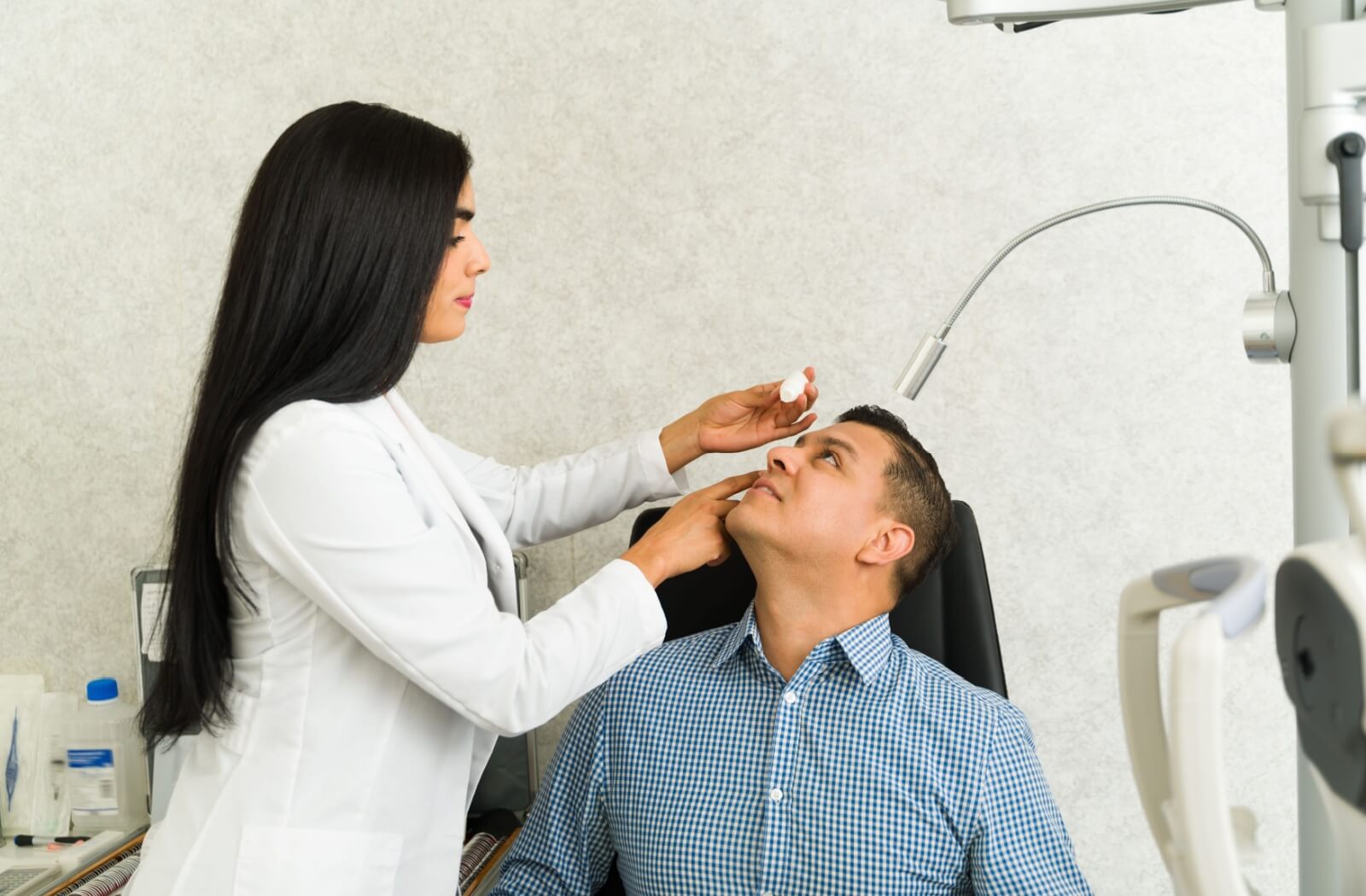 A female optometrist applies a scleral lens to her patient's eye.