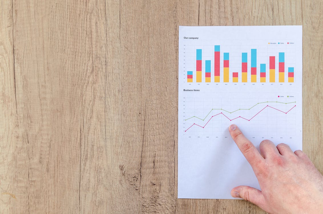 Free Hand analyzing business graphs on a wooden desk, focusing on data results and growth analysis. Stock Photo