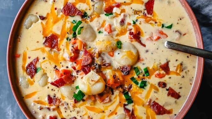 Bacon Cheddar Gnocchi Soup in a reddish-brown bowl.