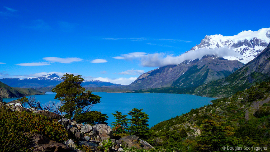 Lake surrounded by green, snowy mountains.