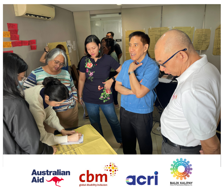  A photo of the Rise and Thrive program team discussing in small groups. One of them is writing notes on a piece of manila paper.  